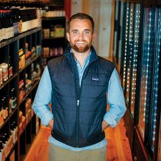 man in front of shelves of wine and  beer