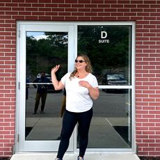 person in white T-shirt smiling and posing in front of doorway