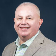 headshot of person in blazer smiling