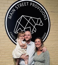 3 people in front of sign and brick wall