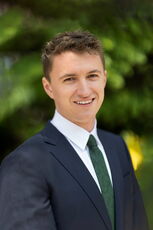 A person wearing a suit and green tie poses.