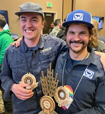 Two people hold awards.