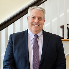 headshot of person in blazer smiling