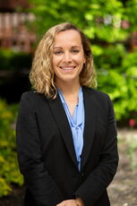 headshot of person in blazer smiling