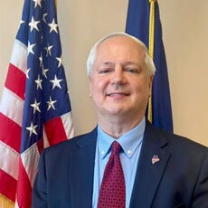 photo of John Butera next to flags