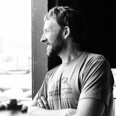 A black and white photo shows a person with arms crossed.