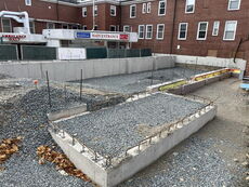 A construction site is in back of a brick building.