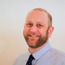 smiling person with blue shirt and tie