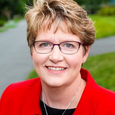 smiling person with red jacket and necklace