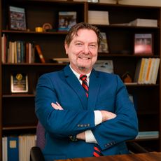 Jim Roche in his office, sitting down with his arms crossed in front of him.