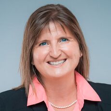 Woman in black blazer and pink shirt.