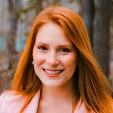 Professional headshot of a woman in pink blazer.