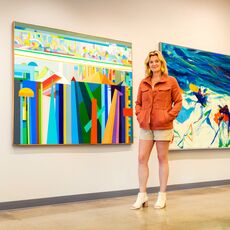 Elizabeth Moss standing in front of paintings in her Falmouth gallery 