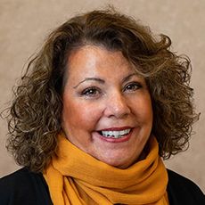 close up of smiling woman with dark hair and orange scarf
