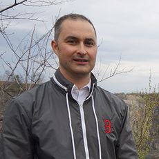 a white man stands next to a weedy quarry