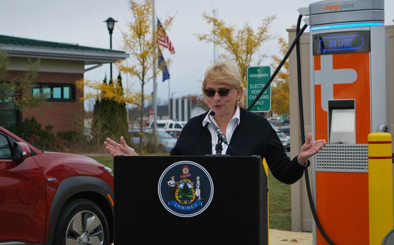 Woman standing in front of electric vehicle charging station