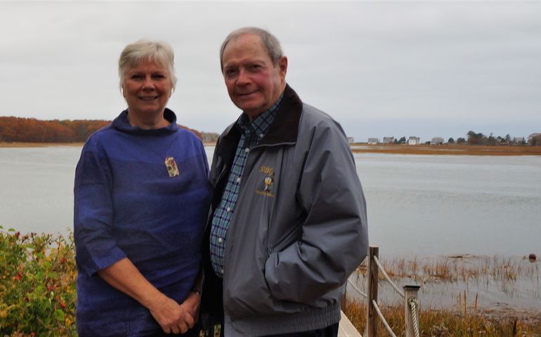 A woman and a man standing with the ocean in the background