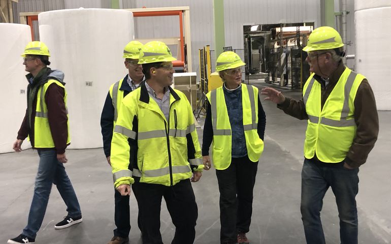 Sen. Angus King, dressed in a safety vest and hard hat talks to half a dozen similarly dressed me in a production area.