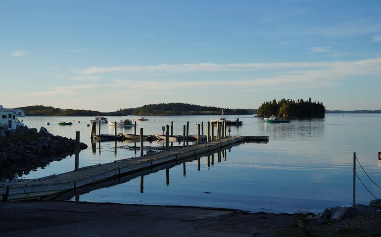 A long dock with boats on blue water