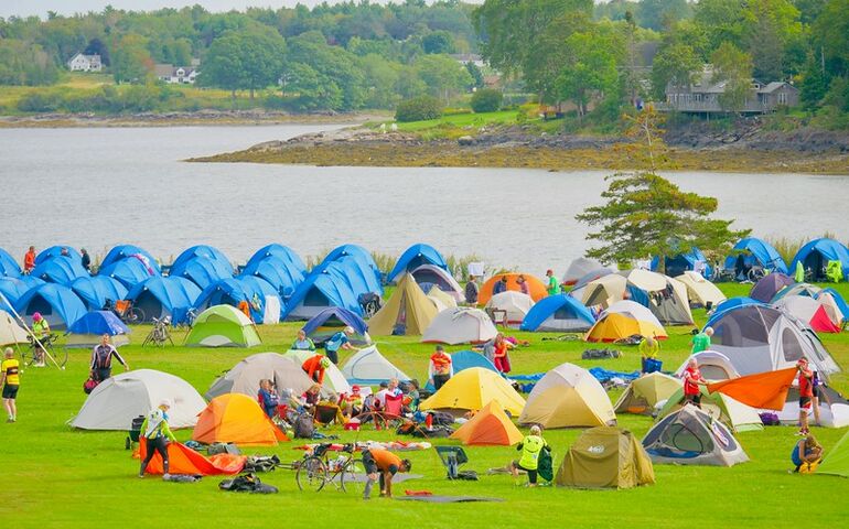 brightly colored tents pitched on grass next to a river