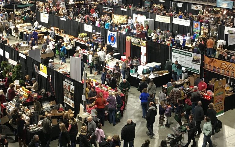 An aerial view of a crowded convention hall full of booths and farm machinery