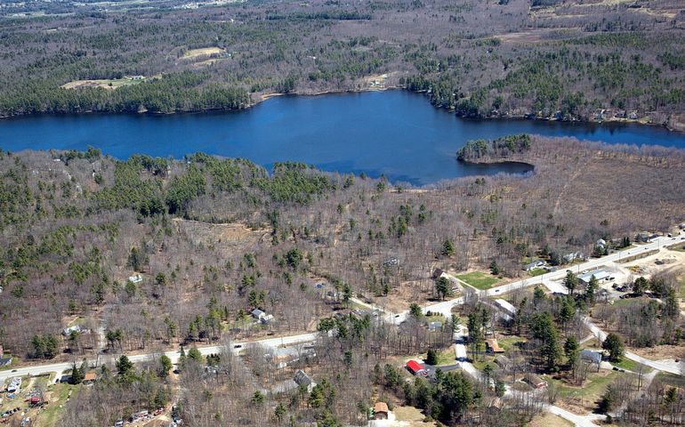 an aerial view of a winter landscape with houses, roads and a bright blue lake