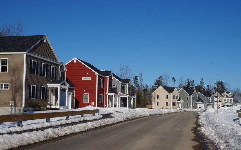 A row of brightly colored brand new houses along a snowy street