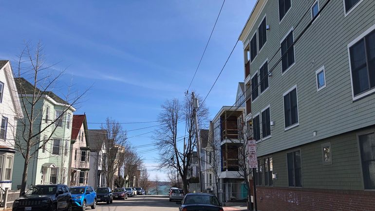 A street with older buildings on the left and a newer apartment building on the right