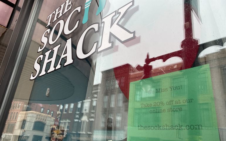 Closed storefront in Portland with a sign directing customers to an ecommerce site.