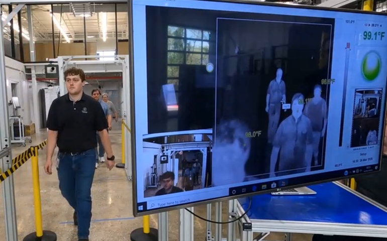 A man walks past a monitor showing an infrared scan of his body