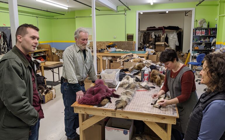 U.S. Rep Jared Golden standing at a table where a group of men and women are manufacturing leather goods