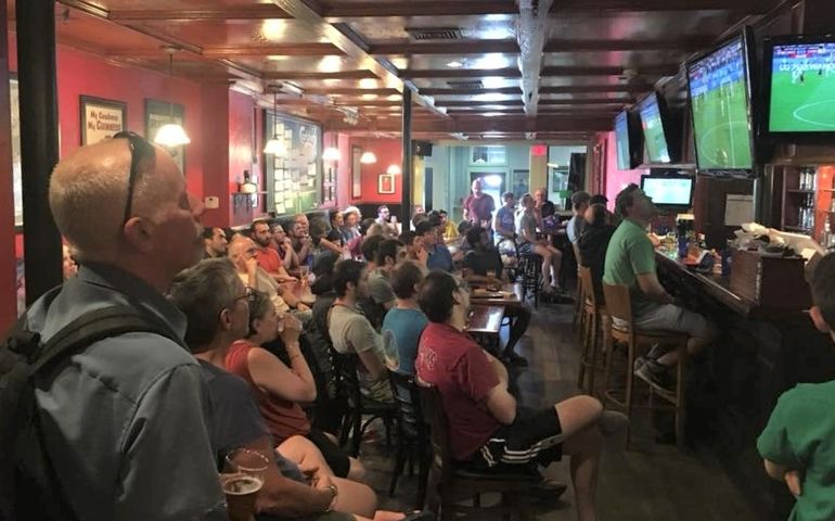 crowd seated at bar watching soccer on TV