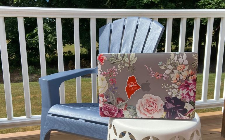 Photo of a laptopon a deck outdoors.