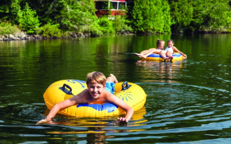 Photo of children having fun on inner tubes on a body of water 