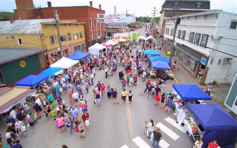 aerial photo of crowd on a street lined with vendor tents