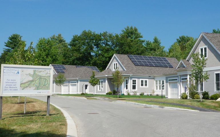 Small bungalow style housing on a curving street with new treess planted on the lawns and a sign that says cumberland crossing