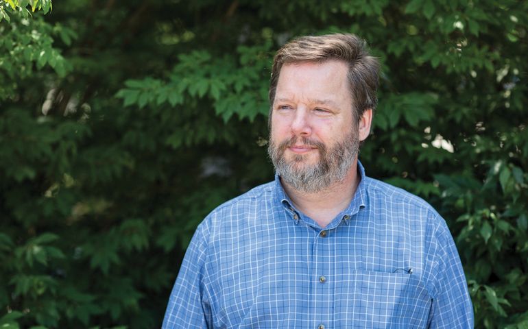 Portrait of Fletcher Kittredge in front of green bushes