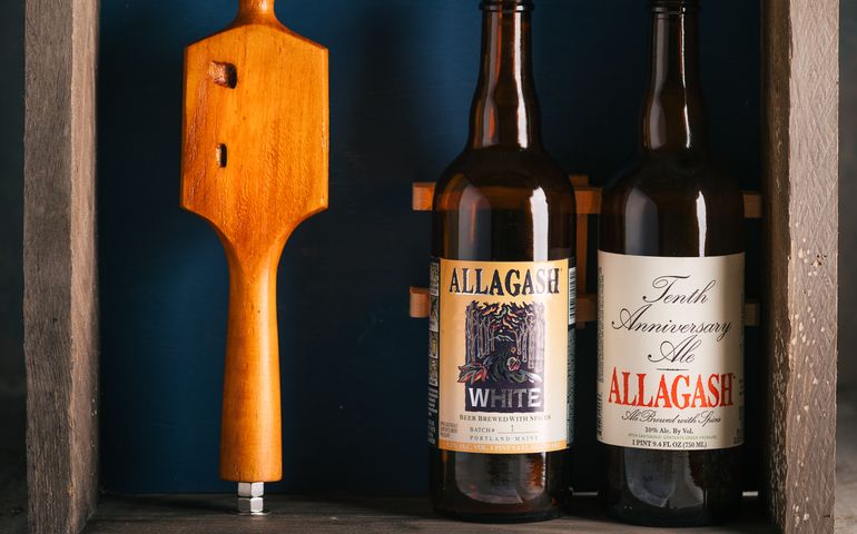 Wooden tap handle next to two bottles of Allagash craft beer