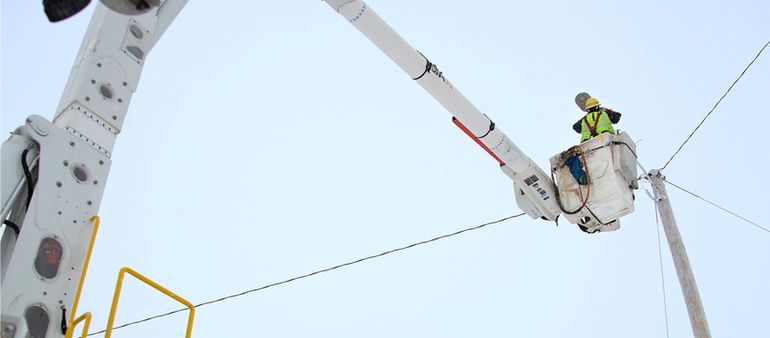 utility worker in cherry picker, near power line