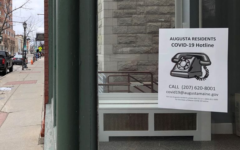 A sign in a downtown window says Augusta residents covid-19 hotline