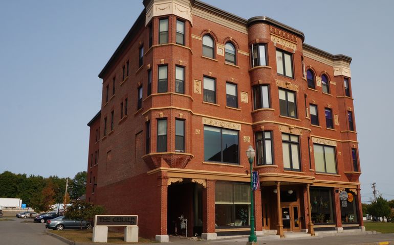 an ornate four-story brick building with big first-floor storefront windows and a sign in front that says the gerald