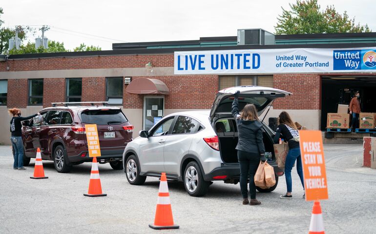 People unloading food from cars for United Way's food drive. Two cars are in the photo.