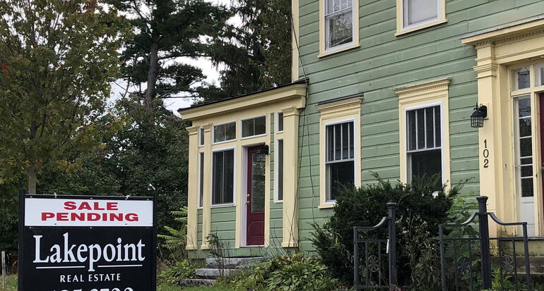 A sign that says sale pending in front of a large house