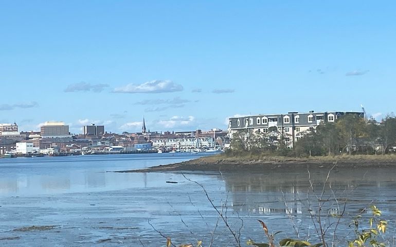 a view across water of Portland with buildings and a churck spire and on the near side an apartment complex on the water