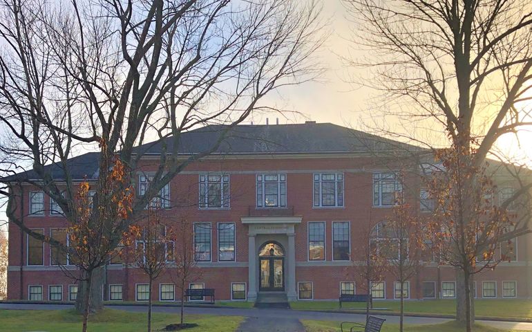 A brick 19th century three-story building, with the sun shinine behind