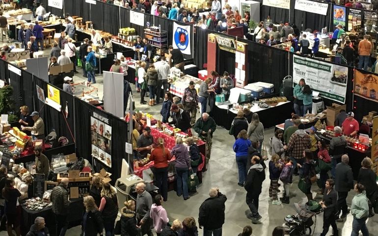an overhead shot shows a crowded convetntion floor with dozens of booths and people milling around