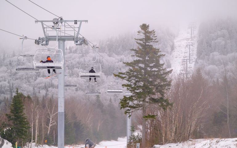 a ski lift with people on it and snow and mountains in the background