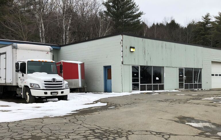 a gray one story industrial buiding with a glassed-in retail area and a bunch of truck bays