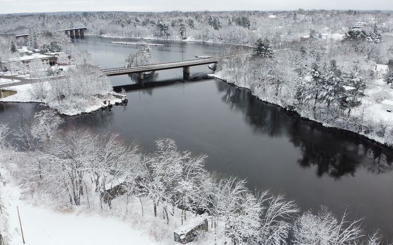 A snowy scene of a river with a couple bridges going across