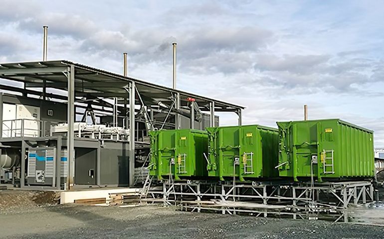 An industrial looking steel structure with three connected containers that look like large industrial dumpsters